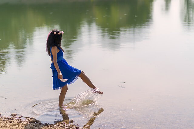 Kobietaw wianku moczy stopę w jeziorze