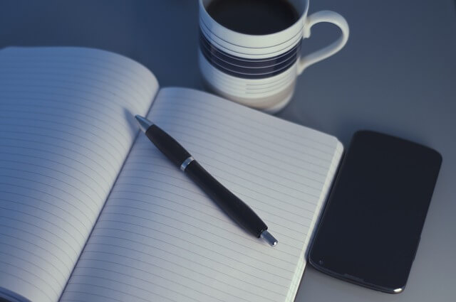 Notatnik, długopis i kawa na biurku