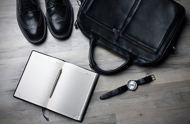 Notatnik, buty, torba i zegarek leżące na podłodze