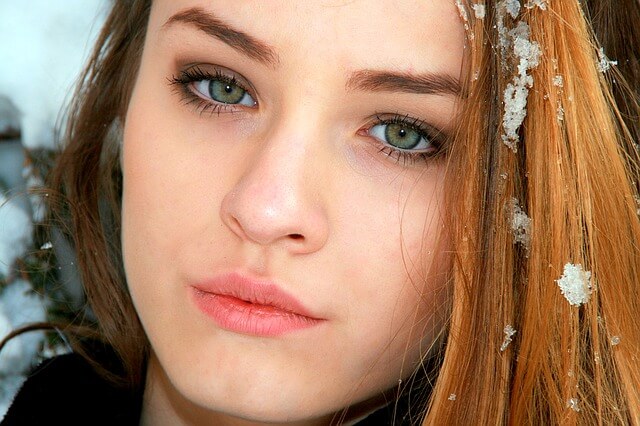 Dziewczyna o zielonych oczach z płatkiem śniegu na włosach