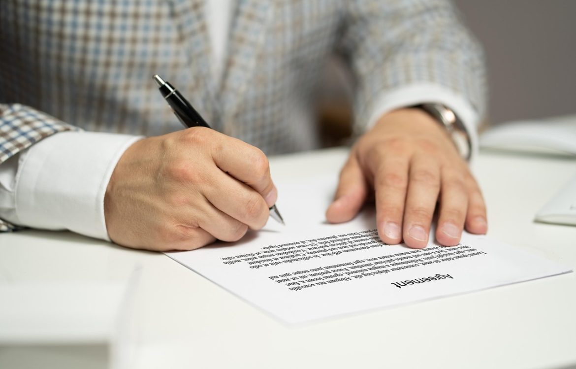 Podpisywanie dokumentu długopisem przy biurku